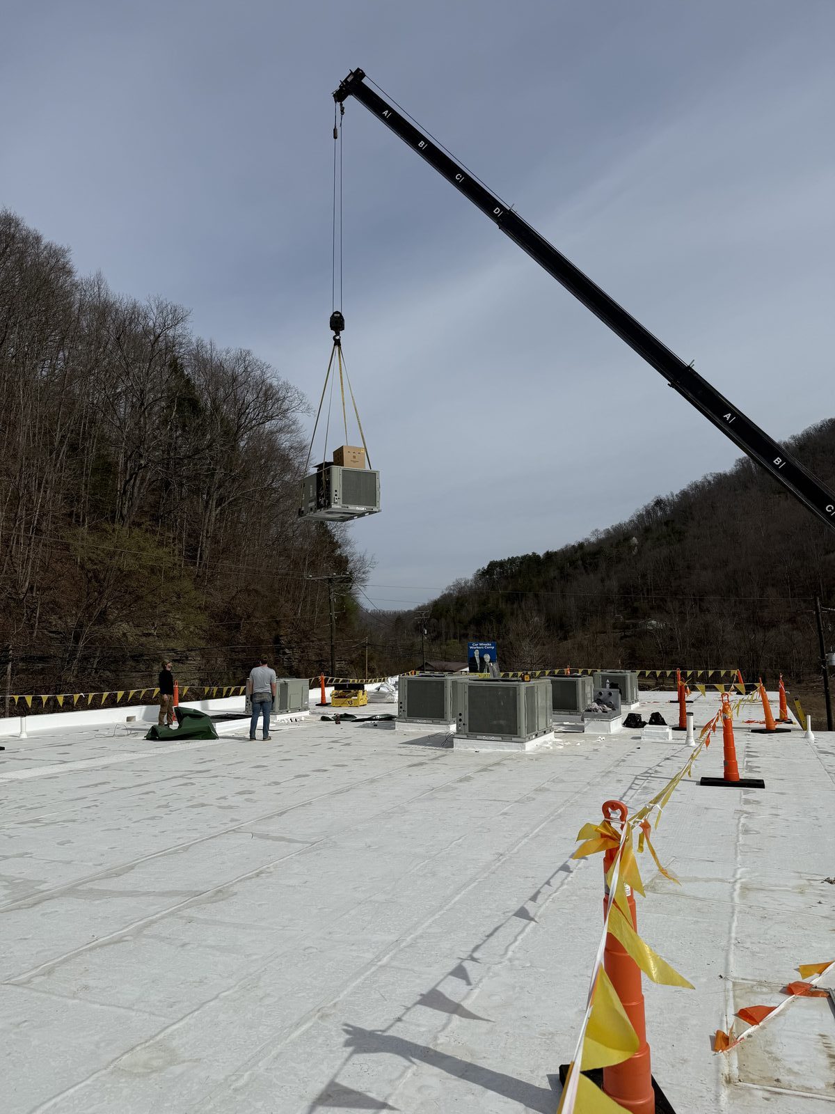 Crane lifting a rooftop HVAC unit during an Elite Heating & Cooling commercial installation